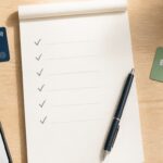 Zwei Bankkarten neben Smartphone und Checkliste für den Kontowechsel